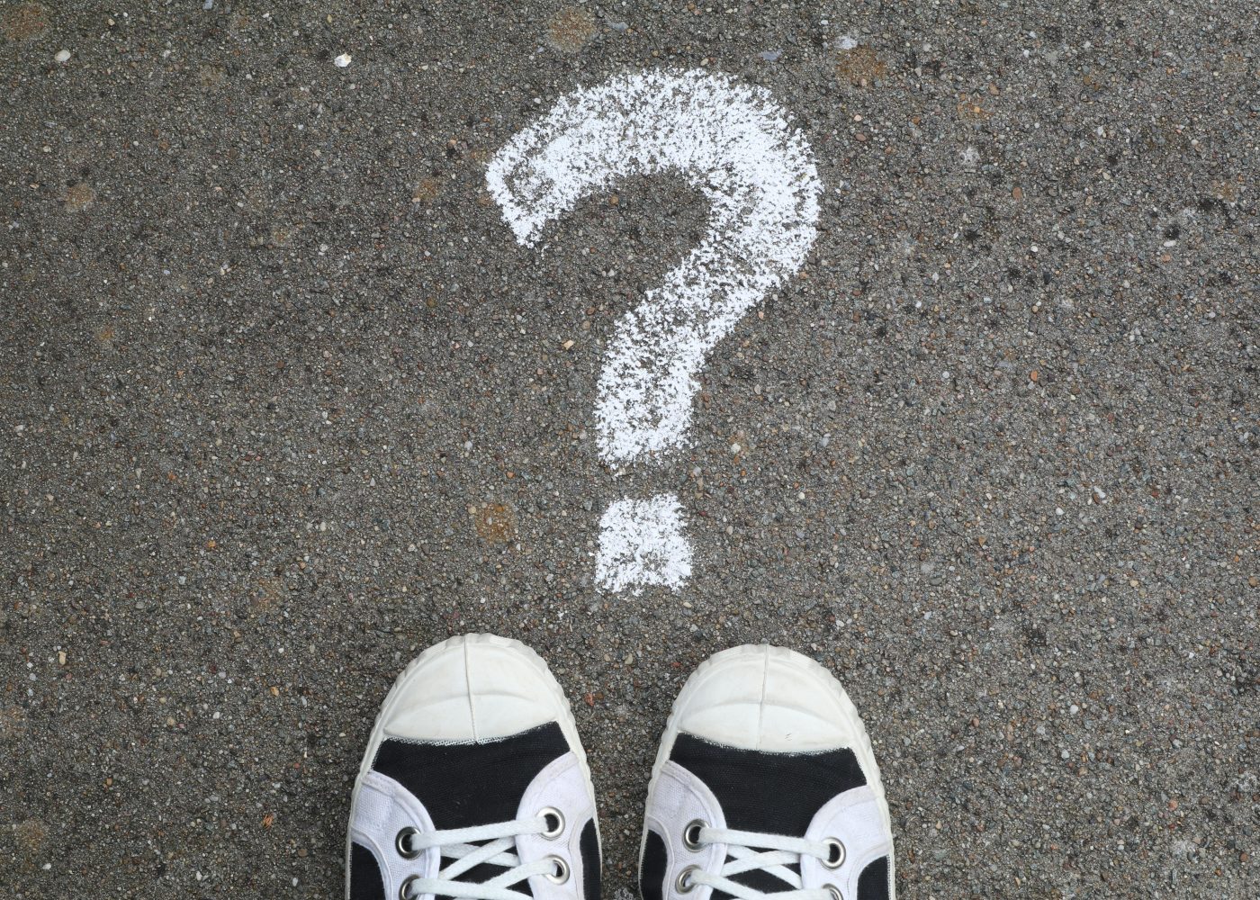 Sneakers on pavement with a chalk question mark, symbolizing curiosity or decisions.